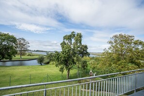 A view of a grassy area with trees and a body of water. - Holiday Apartment "Leuchtturm" – Top Floor, Large Balcony & Panoramic Achterwasser View (Mellenthin)