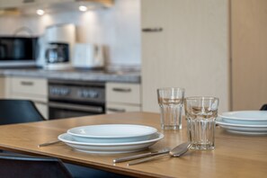 Una mesa de comedor lista con platos, cubiertos y vasos en una cocina moderna.