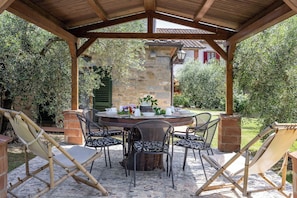 A covered outdoor dining area with a stone wall, wooden beams, and a tiled floor. - Il Cipresso, Casa Martina, Cortona (Cortona)