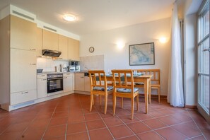Une cuisine compacte avec un coin repas, comprenant une cuisinière, un four et une table à manger avec des chaises.