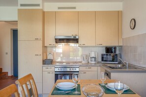 Una cocina moderna con armarios de madera, horno empotrado, microondas y cafetera.