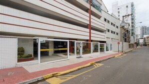 A building with a tiled facade, a covered outdoor seating area with a yellow sign, and a no parking sign. - Blue Mar Apartamento (Guarapari)