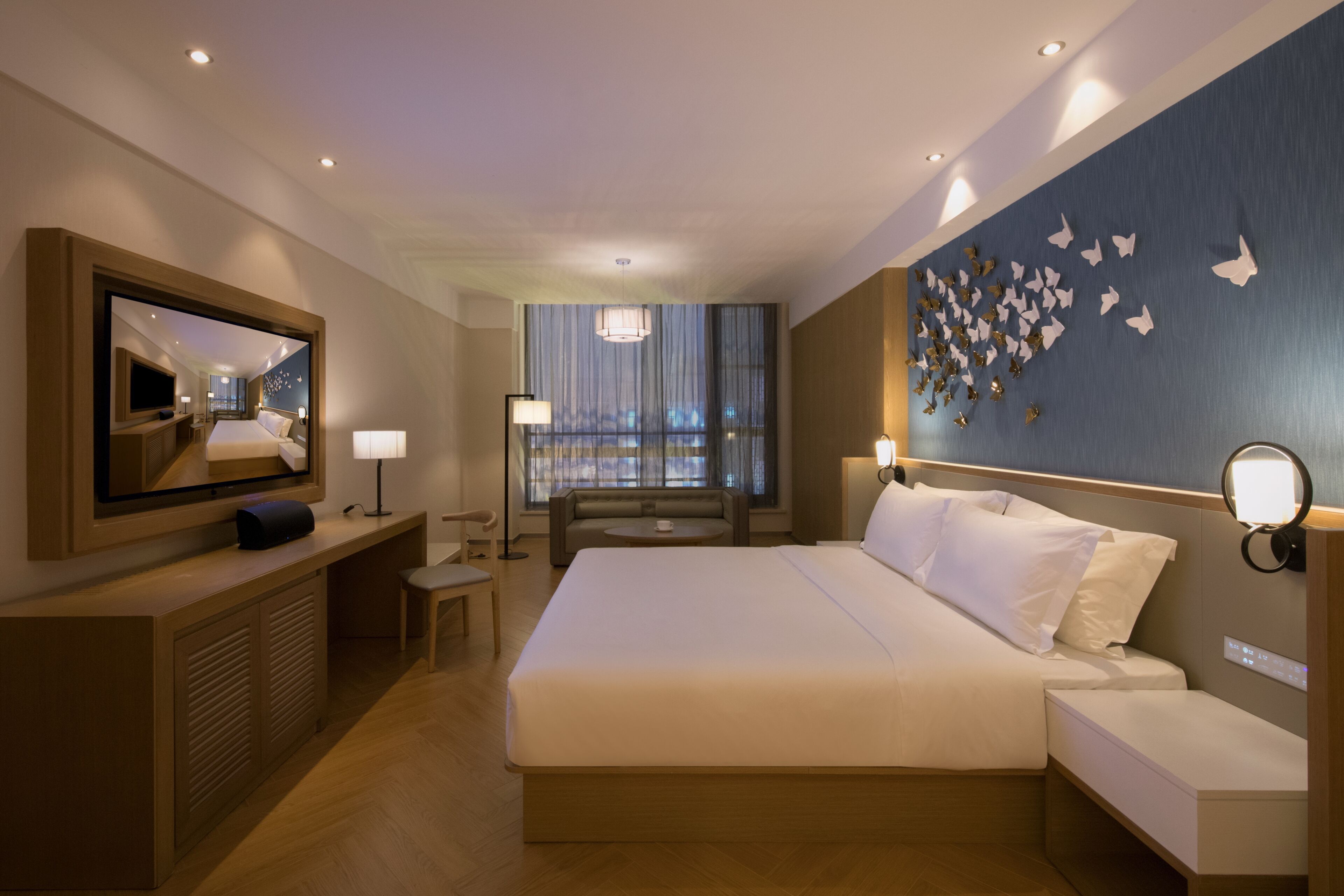 Habitación de hotel con una cama grande, televisión, escritorio y ventana con cortinas.
