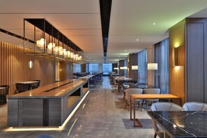 En moderne hotellobby med en lang receptionsdisk, et loungeområde og store vinduer.