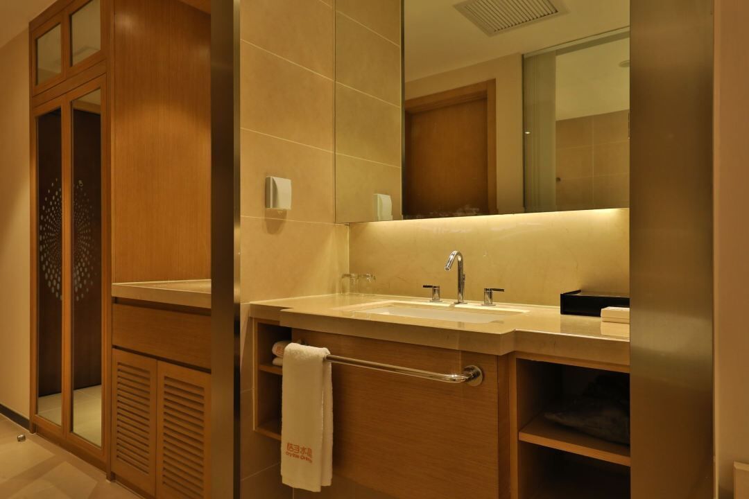 A modern bathroom with a large mirror, a sink, and a towel rack.