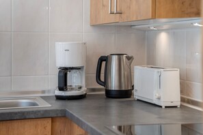 Een keuken met een koffiezetapparaat, een waterkoker en een broodrooster op het aanrecht.
