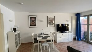 Ein modernes Wohnzimmer mit Essbereich, einem Flachbildfernseher und Kunstwerken an den Wänden.