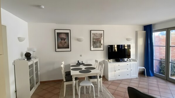 Ein modernes Wohnzimmer mit Essbereich, einem Flachbildfernseher und Kunstwerken an den Wänden.