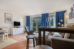 Een moderne woonkamer met een televisie, zitplaatsen en uitzicht op de omgeving.