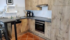 Eine moderne Küche mit Holzschränken, einer Edelstahlspüle und einem eingebauten Backofen.