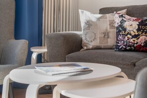 Ein modernes Wohnzimmer mit einem grauen Sofa, einem weißen Couchtisch und einem kleinen Beistelltisch.