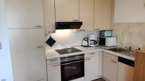 Una cocina moderna con horno integrado, cafetera, microondas y hervidor.