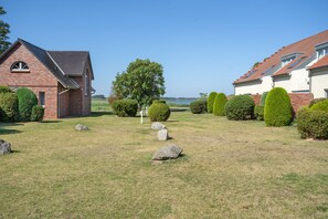A residential area with two houses, a grassy lawn, and a large tree. - “Krienker See” Apartment – Terrace & Nature Views (Mellenthin)