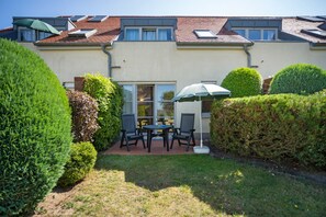 A residential building with a patio area featuring a table and chairs, surrounded by well-maintained hedges. - “Krienker See” Apartment – Terrace & Nature Views (Mellenthin)