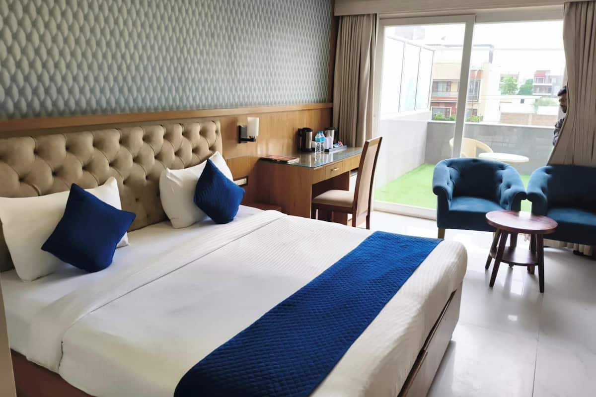 A hotel room with a large bed, a desk, a chair, and a sofa.