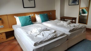 Una habitación de hotel con una cama, mesitas de noche, un espejo y obras de arte en las paredes.