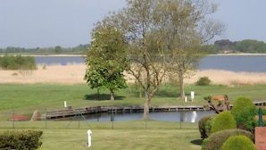 Un campo de golf con un estanque, árboles y un puente de madera.