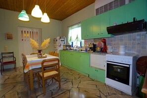 A kitchen with green cabinets, a white stove, and a dining area with a table and chairs. - Villa Helios is a country house in a very quiet area, 200 meters from the sea. (Kantia)