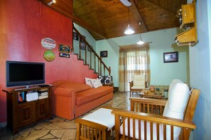 A living room with a sofa, television, wooden furniture, a staircase, and a wall with signs. - Villa Helios is a country house in a very quiet area, 200 meters from the sea. (Kantia)