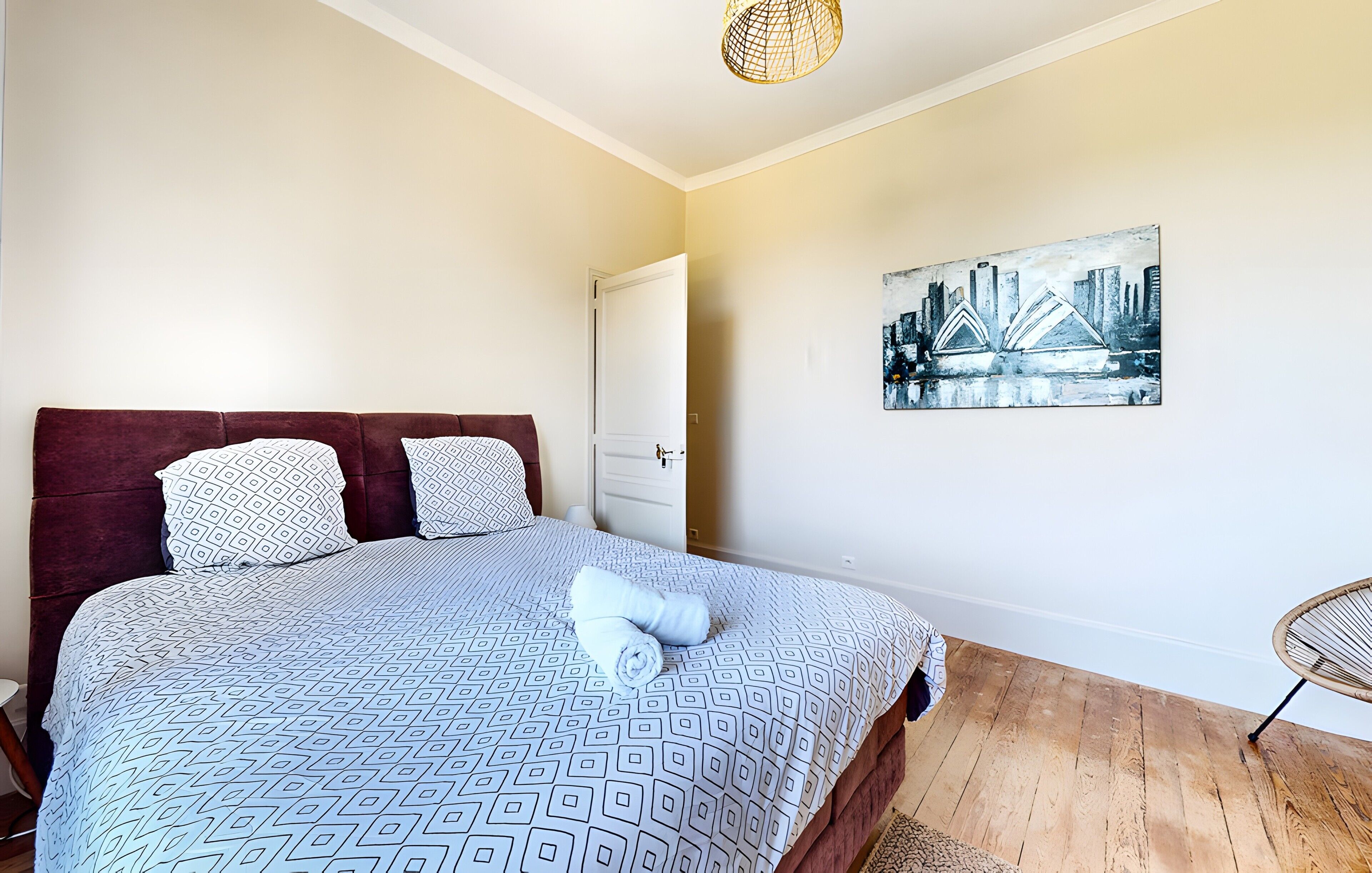 Una camera da letto con un letto, una porta, un quadro e una sedia.