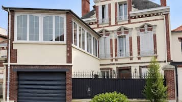 A large, two-story house with a garage, large windows, and a brick facade.