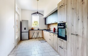 A modern kitchen with a refrigerator, stove, and wooden cabinets. - Villa Sénone – Group Getaway in the Heart of Sens (Sens)
