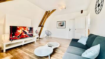 Un salon moderne doté d’un téléviseur à écran plat, de parquet, d’un canapé blanc et d’un design de plafond original.