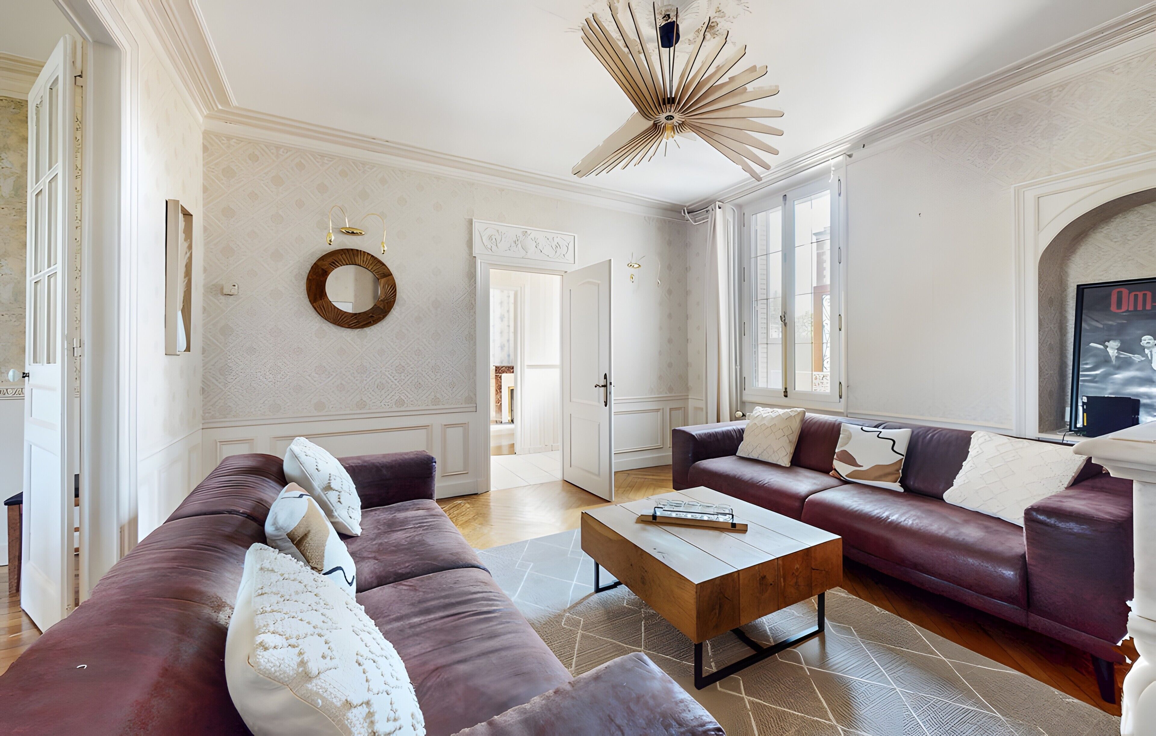 A spacious living room with a large sofa, a coffee table, and a decorative ceiling light.