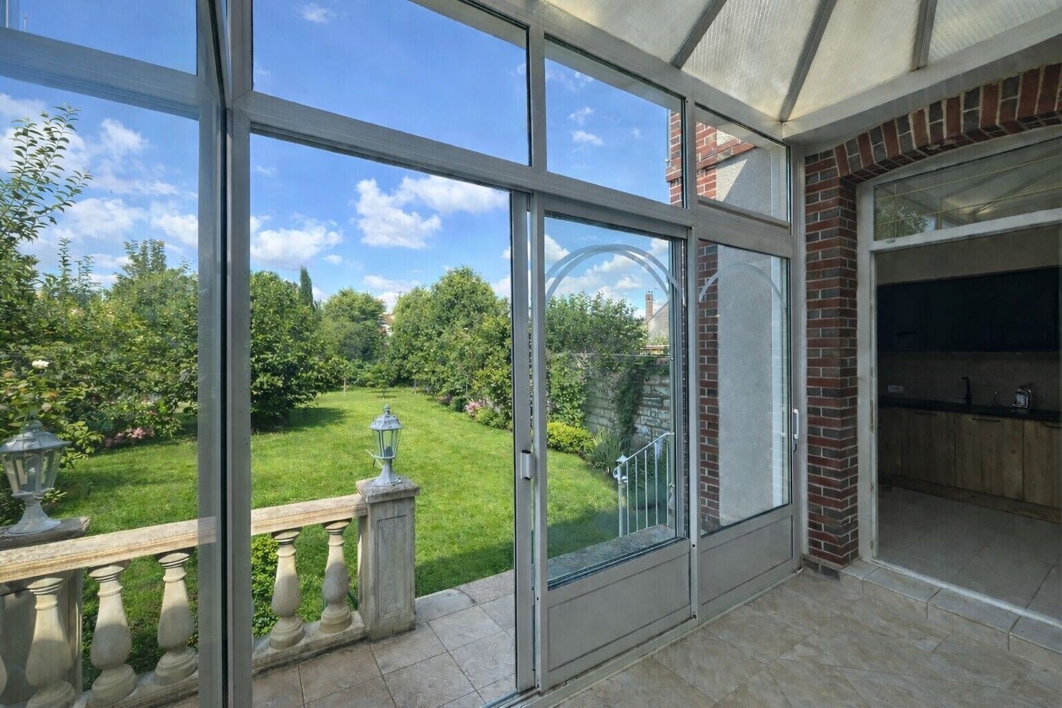 A room with large sliding glass doors, a brick fireplace, and a view of a well-maintained garden.