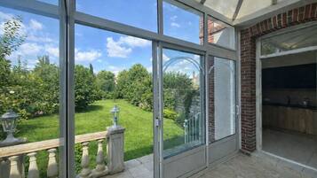 A room with large sliding glass doors, a brick fireplace, and a view of a well-maintained garden.