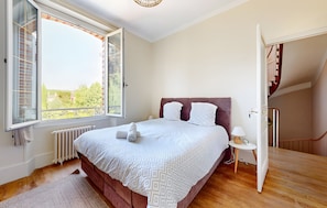 A bedroom with a bed, a window, a radiator, a bedside table with a lamp, and a staircase. - Villa Sénone – Group Getaway in the Heart of Sens (Sens)
