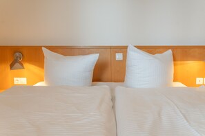 A hotel room with a wooden headboard, two white pillows, and a bed with a striped bedspread. - Apartment “Abendstimmung” – Peaceful Retreat in the Achterland of Usedom (Mellenthin)