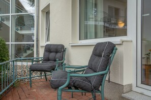 Two green upholstered chairs with cushions on a brick patio. - Apartment “Abendstimmung” – Peaceful Retreat in the Achterland of Usedom (Mellenthin)