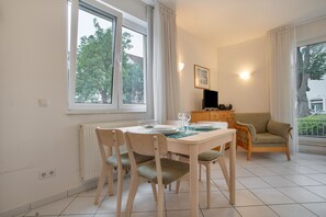 A dining area with a table set for two, a sofa, and a television in the background. - Apartment “Abendstimmung” – Peaceful Retreat in the Achterland of Usedom (Mellenthin)