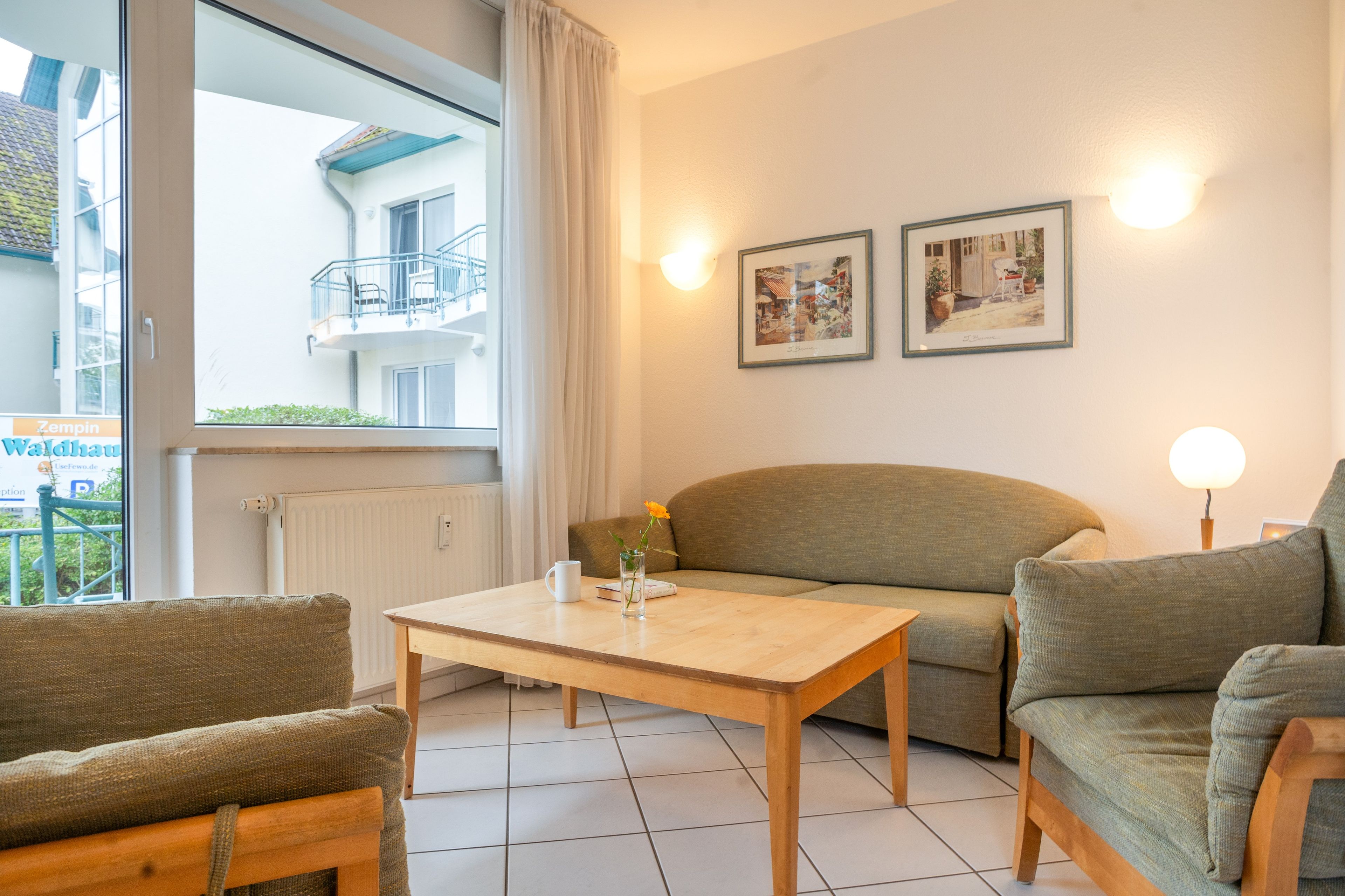 Ein modernes Wohnzimmer mit einer Couch, einem Tisch und zwei gerahmten Bildern an der Wand.