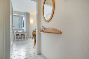 A modern bathroom with a wooden vanity, a mirror, and a tiled floor. - Apartment “Abendstimmung” – Peaceful Retreat in the Achterland of Usedom (Mellenthin)