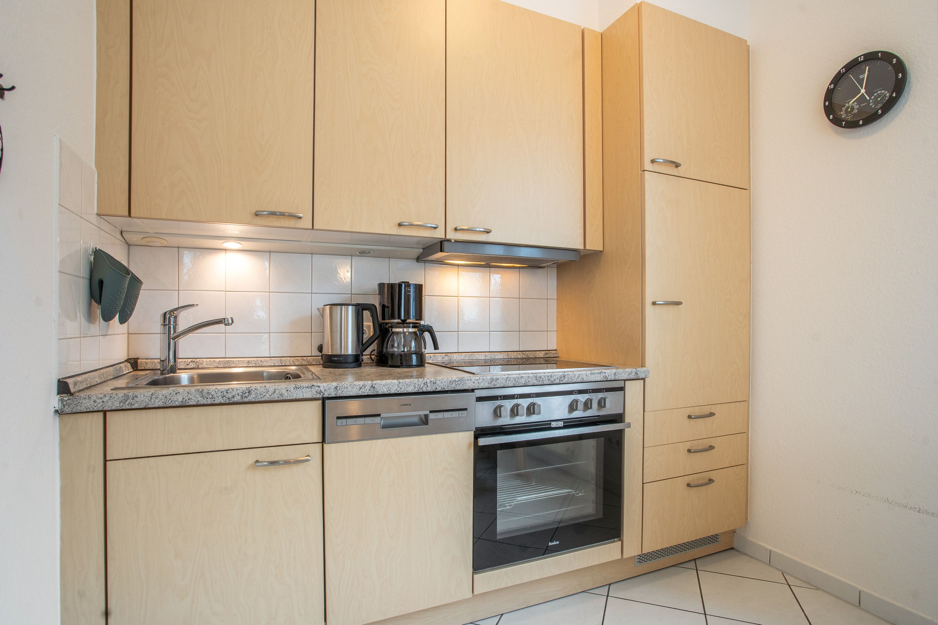 Een moderne keuken met houten kasten, een roestvrijstalen spoelbak, een koffiezetapparaat en een oven.