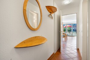 Ein Flur mit einem an der Wand befestigten Holzregal, einem Spiegel und einer Deckenleuchte.