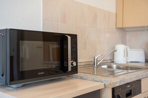 A modern kitchen with a black microwave, a stainless steel sink, and a Bosch dishwasher. - "Kranich" – Bright Holiday Apartment for Nature Lovers in Usedom's Achterland (Mellenthin)