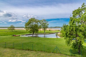 A grassy landscape with a pond, trees, and a clear sky. - Apartment “Achterwasser” – Terrace & Nature Views in Usedom’s Achterland (Mellenthin)