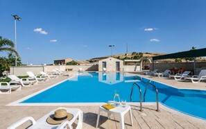 Area piscina con lettini e un piccolo edificio, probabilmente un bar a bordo piscina o spogliatoio.