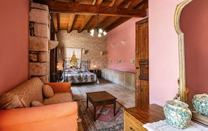 A cozy room with a stone wall, a bed with a canopy, a wooden ceiling, and a large mirror. - Vacation Home in Comiso with 3 bedrooms sleeps 7 (Comiso)