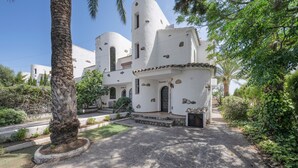 Un bâtiment blanc, doté d’un dôme et d’une porte, entouré de verdure.