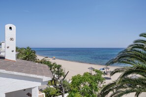 Blick auf einen Strand mit einem weißen Gebäude, Palmen und einem klaren Himmel.
