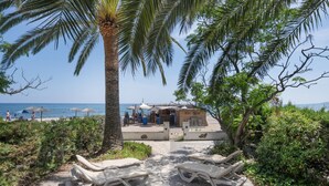 Un espace aménagé au bord de la plage, avec des chaises longues, un petit bâtiment et une vue sur la mer.