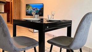 Un comedor con una mesa dispuesta para dos, un televisor en la pared y vistas al exterior.