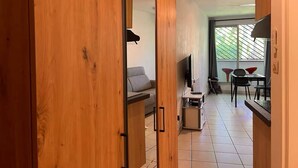 Un interior moderno con armarios de madera, un sofá, un televisor y un comedor con sillas.