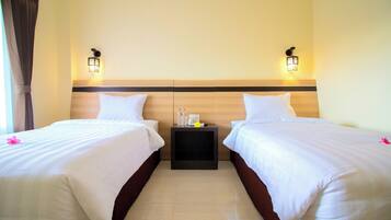 A hotel room with two beds, a nightstand with a lamp, and a wooden headboard.