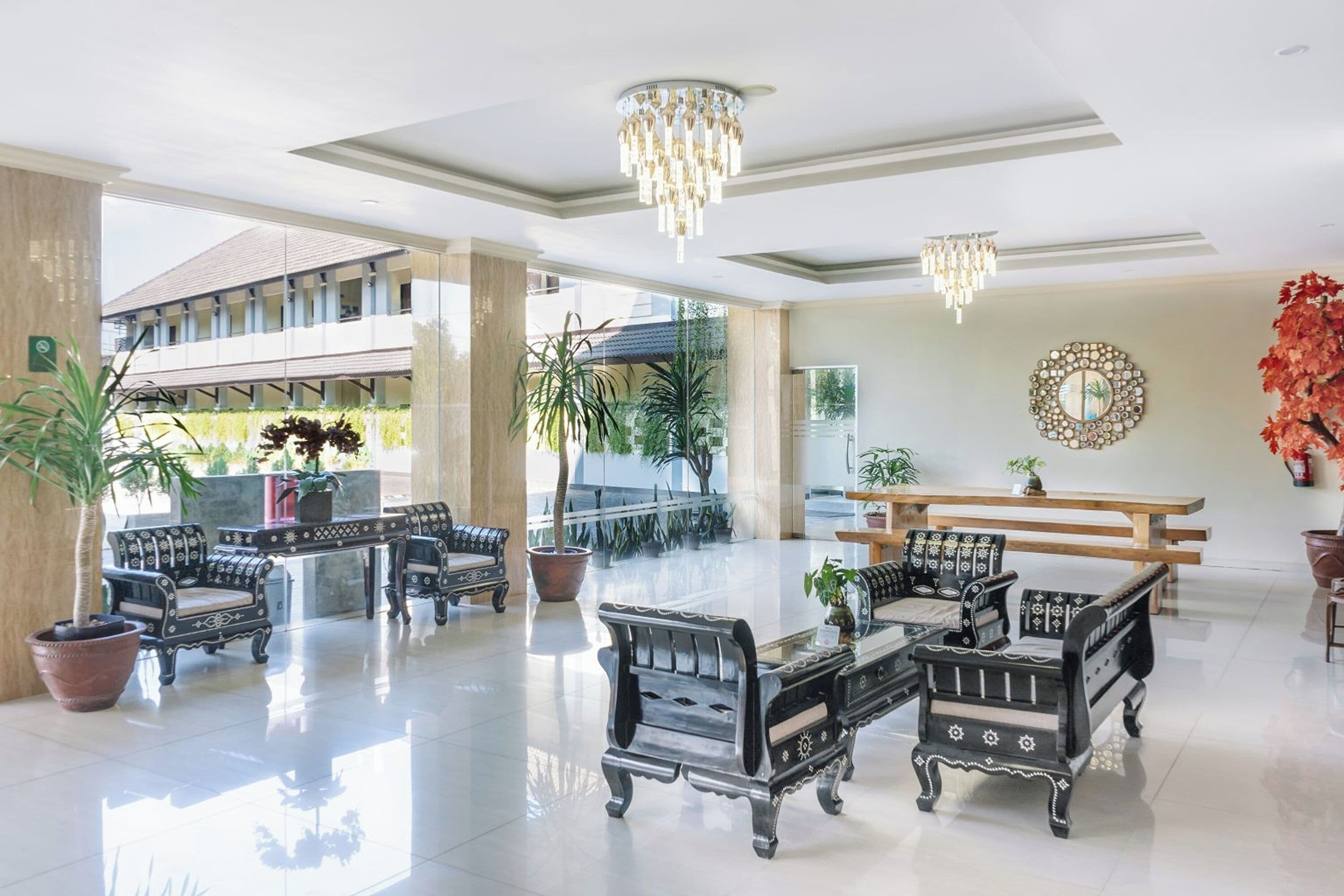 A spacious lobby with ornate black furniture, a chandelier, and a large mirror on the wall.