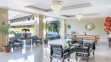A spacious lobby with ornate black furniture, a chandelier, and a large mirror on the wall.